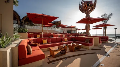 Dance floor sofas under red umbrellas at Zumana Beach Club