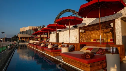 Ocean-edge daybeds along the infinity pool at Zumana Beach Club at sunset