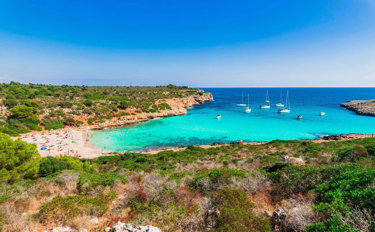 The sandy beach and anchored yachts at Cala Varques