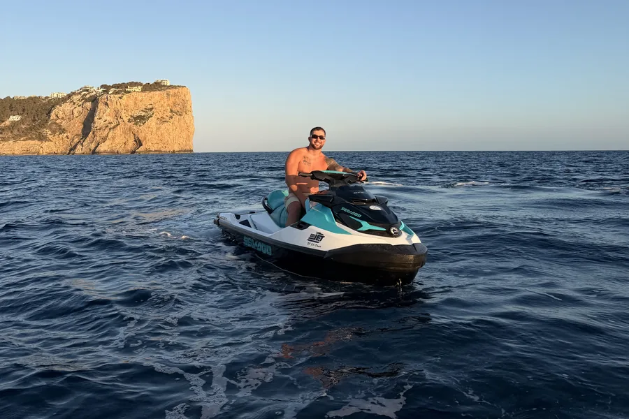 A rider on a Sea-Doo jet ski on flat water off the Mallorcan coast at golden hour